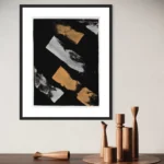 Abstract acrylic composition featuring gold and white strokes on a black background, framed.