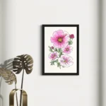 Vibrant pink and white watercolor flowers in a black frame on a white wall.