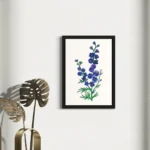 Watercolor blue and purple flowers in a black frame against a white wall.