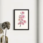 Watercolor floral sketch of pink blossoms in a black frame on a white wall.