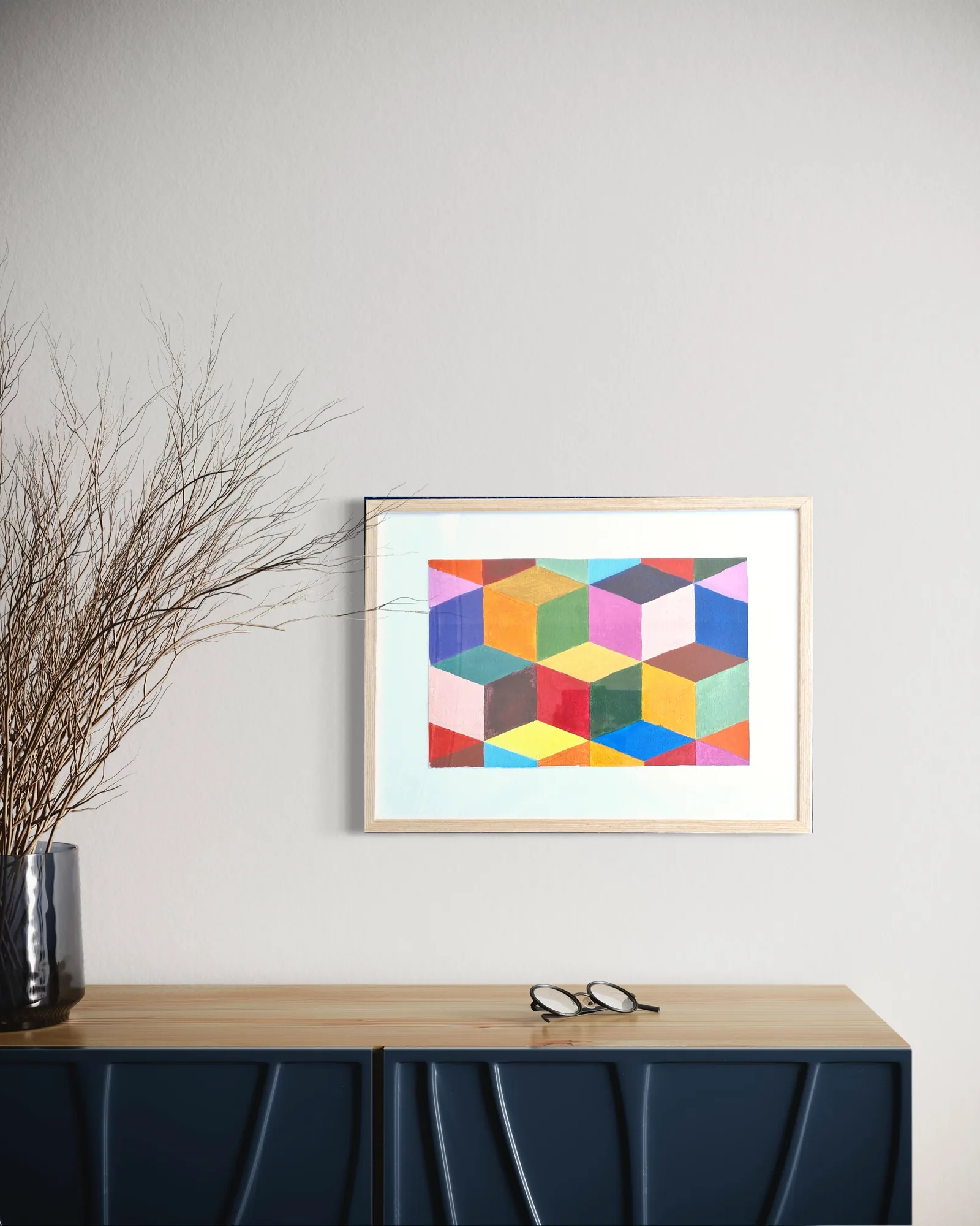 Colorful geometric abstract composition in a white frame against a light wall.