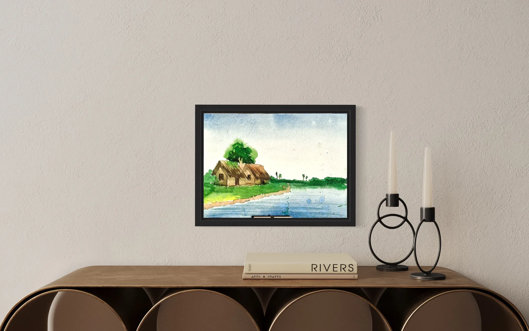 Watercolor scene of green huts by a blue river under a bright sky, in a black frame.